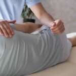 Physiotherapist assisting athlete with knee injury rehabilitation using resistance band physiotherapy in a clinic